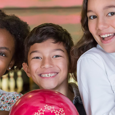 kids smiling holding red bowling balls
