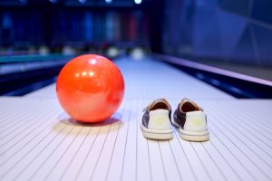 bowling ball and bowling shoes next to each other on a lane in preparation for bowling games